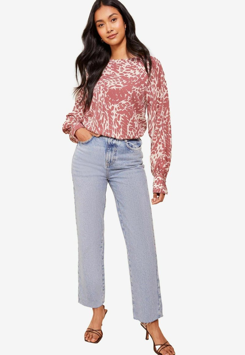 Top a maniche lunghe, rosa tie-dye abbinato a jeans azzurri a gamba dritta e sandali neri con cinturini. Tessuto morbido e vestibilità rilassata.