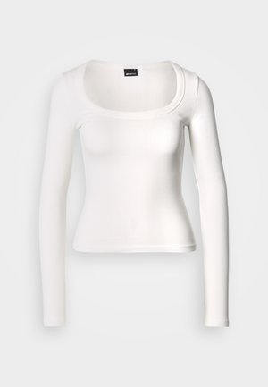 Haut blanc à manches longues avec un col arrondi. Confectionné en tissu côtelé, il présente une coupe ajustée et une texture lisse avec une finition sans coutures.