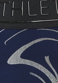 Marineblaue Stoff mit einem metallisch-silbernen abstrakten Muster, versehen mit einem schwarzen, strukturierten Bund, in den das Wort "ATHLETE" in glänzenden Buchstaben geprägt ist.