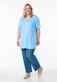 Camiseta azul claro con cuello en V y mangas cortas combinada con jeans azules holgados. La camiseta tiene una textura suave y los jeans están ligeramente deslavados.