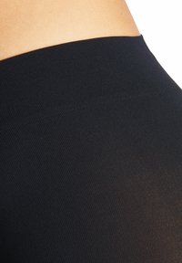 Tessuto a coste nero, design aderente, superficie liscia e vita alta. Focus sui materiali e sullo stile funzionale.