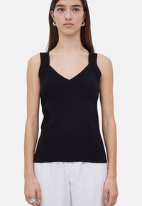 Top negro sin mangas con escote en V y tirantes gruesos. Fabricado con una tela suave, tiene un diseño entallado y un estilo minimalista.