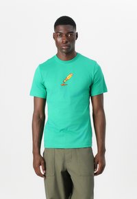 Grøn bomulds T-shirt med rund hals, korte ærmer og et farverigt grafisk motiv af en dryppende malerflaske på brystet.
