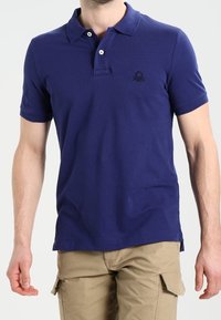 Polo shirt blu navy in cotone, con un placket a due bottoni, maniche corte e un sottile logo ricamato sul petto.