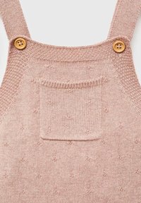 Strickoverall in Rosa mit verstellbaren Trägern, Holzknöpfen und einer Vordertasche, die ein strukturiertes Muster und kleine Akzentpunkte aufweist.