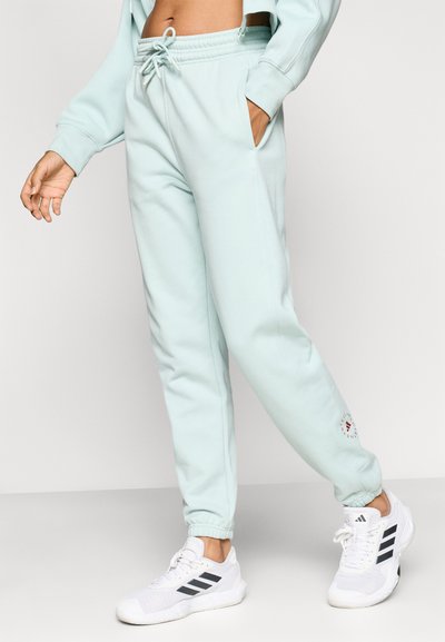 Φαρδιά παντελόνια φόρμας σε ανοιχτό μέντας χρώμα με ελαστική μέση, κορδόνι, πλαϊνές τσέπες και κυκλικό λογότυπο στο κάτω μέρος του ποδιού.