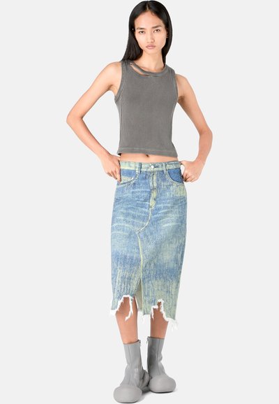 Top in morbido grigio a coste con dettagli cut-out, abbinato a una gonna di jeans blu sbiadita con orlo sfrangiato. Stivaletti grigi alla caviglia completano il look.