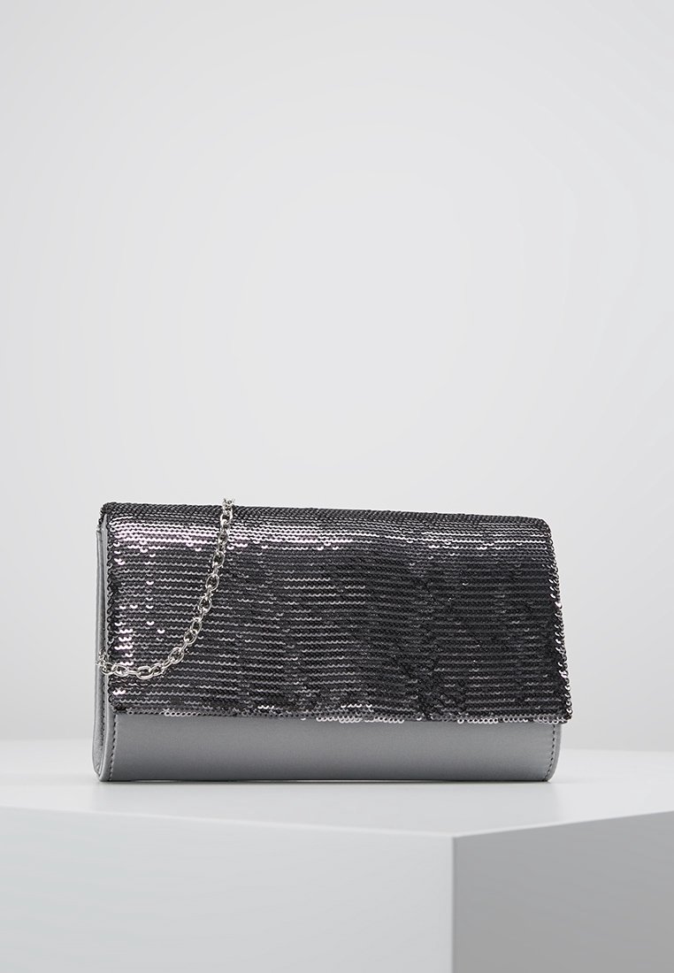 Stříbrná peněženka s flitry na hladkém šedém podkladu, s řetízkem a obdélníkovým tvarem. Texturovaný, lesklý povrch.