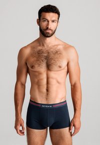 Herrars mörkblå boxerkalsonger med en åtsittande design, i kombination med en logoband med röda och vita ränder. Tillverkade av mjukt tyg, de har en slät textur.