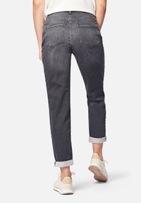 Jeans de mezclilla gris oscuro con un corte relajado, puños enrollados y dos bolsillos traseros. Presentan costuras en contraste y una cinturilla de altura media.