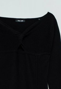 Schwarzes Strickoberteil mit einem V-Ausschnitt und einem Twist-Detail an der Vorderseite sowie langen Ärmeln. Hergestellt aus weichem, strukturiertem Stoff. Markenlabel sichtbar.