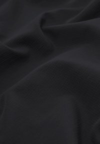 Tissu sombre avec une texture subtile en quadrillage, présenté avec des plis doux et de légers reflets de lumière mettant en valeur la surface du matériau.