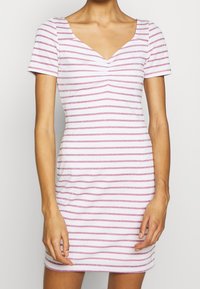 Robe à manches courtes blanche avec des rayures horizontales roses et argentées ; décolleté en V, forme ajustée et texture de tissu douce.