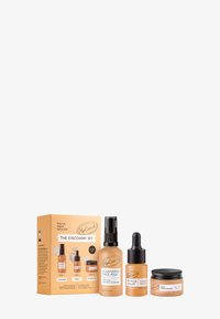 Entdeckungsset mit drei Hautpflegeprodukten: eine transparente Sprühflasche, eine orangefarbene Tropfflasche und ein schwarzes Glas, alle mit minimalistischen Etiketten.