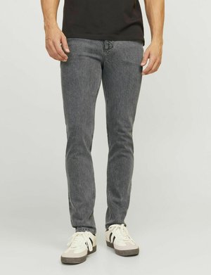 Gray denim jeans with a fitted design, featuring five-pocket styling and subtle whiskering. Paired with white sneakers.