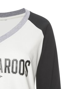 White cotton shirt featuring black raglan sleeves and a grey neckline, with a prominent printed text design on the front in black and grey.