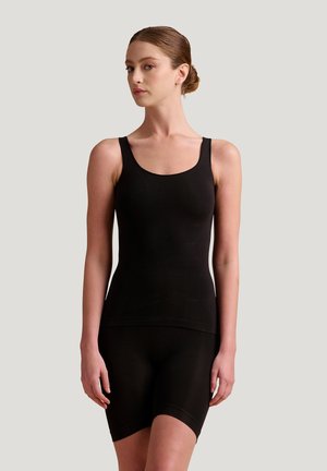 Top senza maniche nero abbinato a shorts a vita alta, realizzato in un materiale liscio e elastico. Design semplice, senza pattern visibili o accessori.