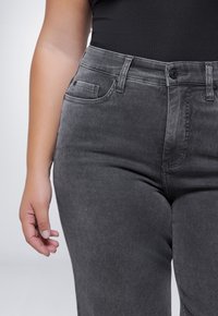 Hoge taille, donkergrijze jeans van denim. Kenmerken zijn onder andere voortassen, knoopsluiting en een soepele textuur.