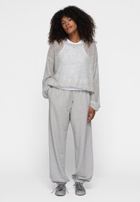 Grå fleece sweatshirt med raglanærmer og rund hals, parret med grå sweatpants med elastisk talje og manchetter.