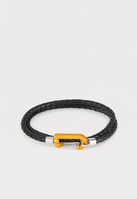 Svart flätad läderarmband med ett silvermetallspänne med en orange accent. Designen är cirkulär och texturerad med intrikata detaljer.