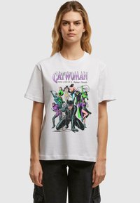 Hvid bomulds t-shirt med et farverigt grafiktryk af forskellige figurer, herunder Catwoman. Designet fremhæver kraftige linjer og livlige farver.