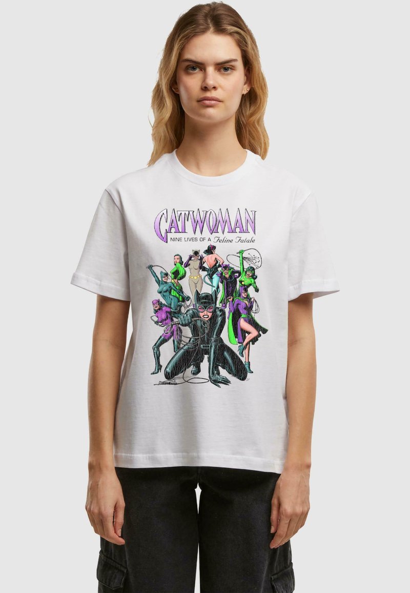 Hvid bomulds t-shirt med et farverigt grafiktryk af forskellige figurer, herunder Catwoman. Designet fremhæver kraftige linjer og livlige farver.