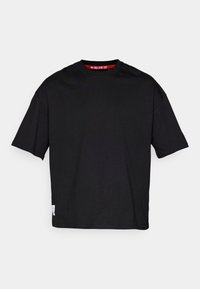 Sort bomulds T-shirt med rund halsudskæring, korte ærmer og et mærke på den nederste kant. Stoffet er glat og let.