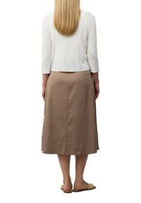 Weiße, strukturierte Bluse mit Dreiviertelärmeln, kombiniert mit einem knie-langen, beigen A-Linien-Rock, der aus glattem Stoff gefertigt ist und eine einfache Silhouette aufweist.