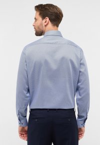 Camicia da uomo a maniche lunghe di colore azzurro chiaro, con un piccolo motivo geometrico, polsini abbottonati e colletto strutturato. Viene mostrata la vista posteriore.