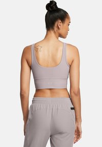 Lichtgrijze geribbelde sportbeha met brede schouderbanden en een ronde achterkant. Draagt samen met bijpassende lichtgrijze sportbroek, voorzien van een elastische tailleband.