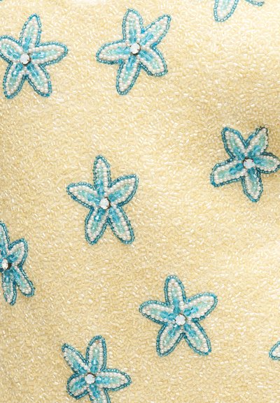 Tissu crème décoré de motifs floraux en forme d'étoile ornés de perles bleues et blanches, chacun avec un strass clair central.