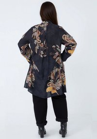 Long black tunic with vibrant paisley embroidery in gold, orange, and white. Features wide sleeves and a split back for ease of movement.
