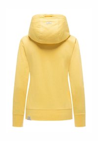 Sweat à capuche jaune à manches longues avec poignets et ourlet côtelés, vu de dos, doté d'une capuche et de petites étiquettes en tissu sur la capuche et l'ourlet.