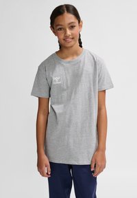 Grå bomulds-t-shirt med korte ærmer og rund hals. Har et lille hvidt "hummel" logo på venstre bryst. Enkel design og pasform.