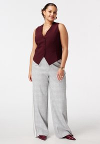 Bordeaux mouwloos vest met knoopsluiting aan de voorkant; gecombineerd met lichtgrijze geruite wijde broek met zijstreep; zachte stoftextuur.