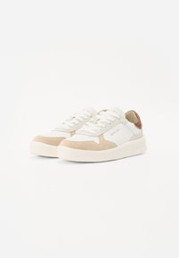 Hvite og beige lær sneakers med semsket detaljer, flat såle, rund tå og snøring. Merkevaren logo synlig på siden.