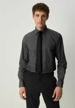 Black and gray checkered dress shirt with a pointed collar, paired with a solid black tie. Slim-fit design, textured fabric, long sleeves.