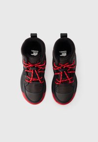 Schwarze und rote Winterstiefel mit roten Schnürsenkeln und Zuglaschen, von oben auf einem weißen Hintergrund betrachtet, mit sichtbarem Markennamen "Sorel" innen.