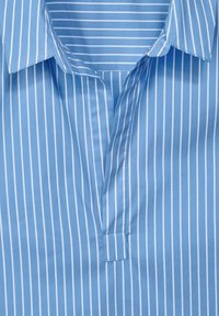 Ljusblå skjorta med krage som har vita vertikala ränder, en design utan knappar fram, med en mjuk textur och en skarp finish.
