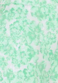 Blommig tyg i ljusgröna nyanser med överlappande blommönster, med en mjuk, genomskinlig struktur och en subtil transparent bakgrund.