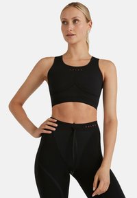 Czarny sportowy top typu crop z dopasowanym krojem, teksturowaną tkaniną i bezszwowym wyglądem. Na klatce piersiowej znajduje się czerwone logo.