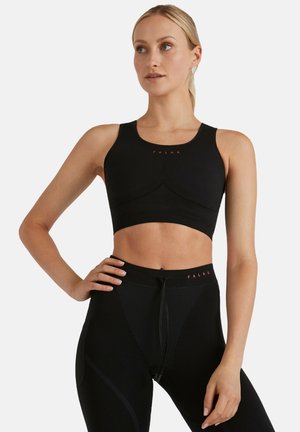 Czarny sportowy top typu crop z dopasowanym krojem, teksturowaną tkaniną i bezszwowym wyglądem. Na klatce piersiowej znajduje się czerwone logo.