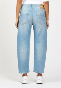 Light blue, wide-leg denim jeans with a medium rise, featuring two back pockets, a brand tag on the waistband, and a raw hem at the ankles.
