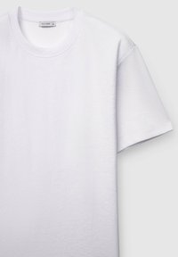 Weißes T-Shirt mit kurzen Ärmeln aus strukturiertem Stoff, mit rundem Ausschnitt und lockerem Schnitt. Etikett mit der Aufschrift "ALLIOPE".