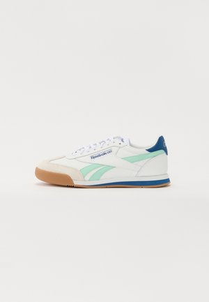 Biały niski sneaker Reebok z jasnorozem bocznymi pasami, niebieskim akcentem na pięcie, gumową podeszwą i zapięciem na sznurowadła, widziany z boku.