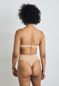 Nude bra and high-waisted brief set, seamless design, adjustable straps, soft texture, and subtle stitching details.