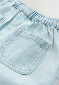 Pantaloni scurți de denim albastru deschis cu talie elastică adunată și o buzunar în spate cu cusături maro deschis și textură netedă.