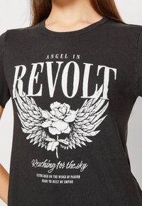 Černé bavlněné tričko s bílým grafickým designem křídel a růže, s textem "Anděl v revolte" a "Žádaní po nebi."