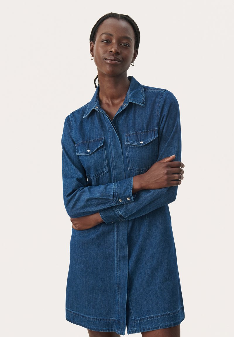 Denim shirt dress featuring a button-down front, long sleeves, two chest pockets, and a relaxed fit in a medium blue wash.