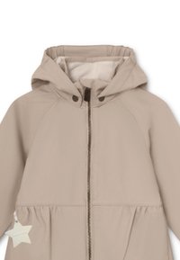 Beige hettejakke med glidelås foran, elastiske mansjetter og samlet midje. Har en liten stjerneakcent på venstre side. Glatt tekstur.